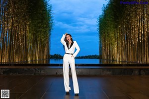 A woman in a white suit standing next to a pool.