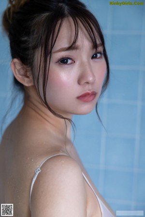A naked asian woman sitting in a bathtub with water.