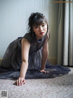 A woman laying on top of a bed next to a window.