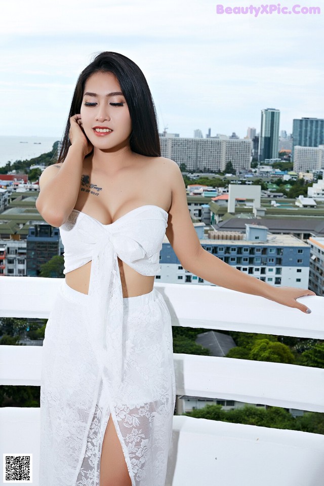 A woman in a white dress standing on a balcony.