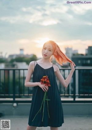 A woman laying on a bed with a flower in her hand.